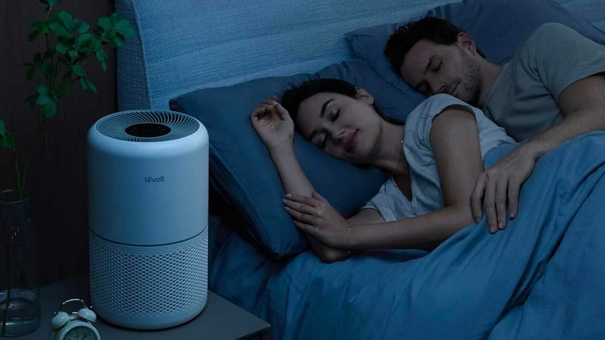 Camera da letto di notte con una coppia che dorme e un purificatore d'aria acceso accanto al letto